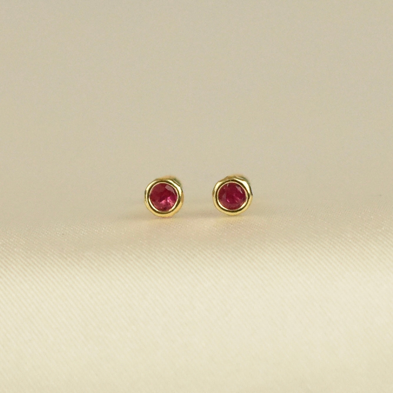 Broquel bisel con zirconia roja en oro 10k