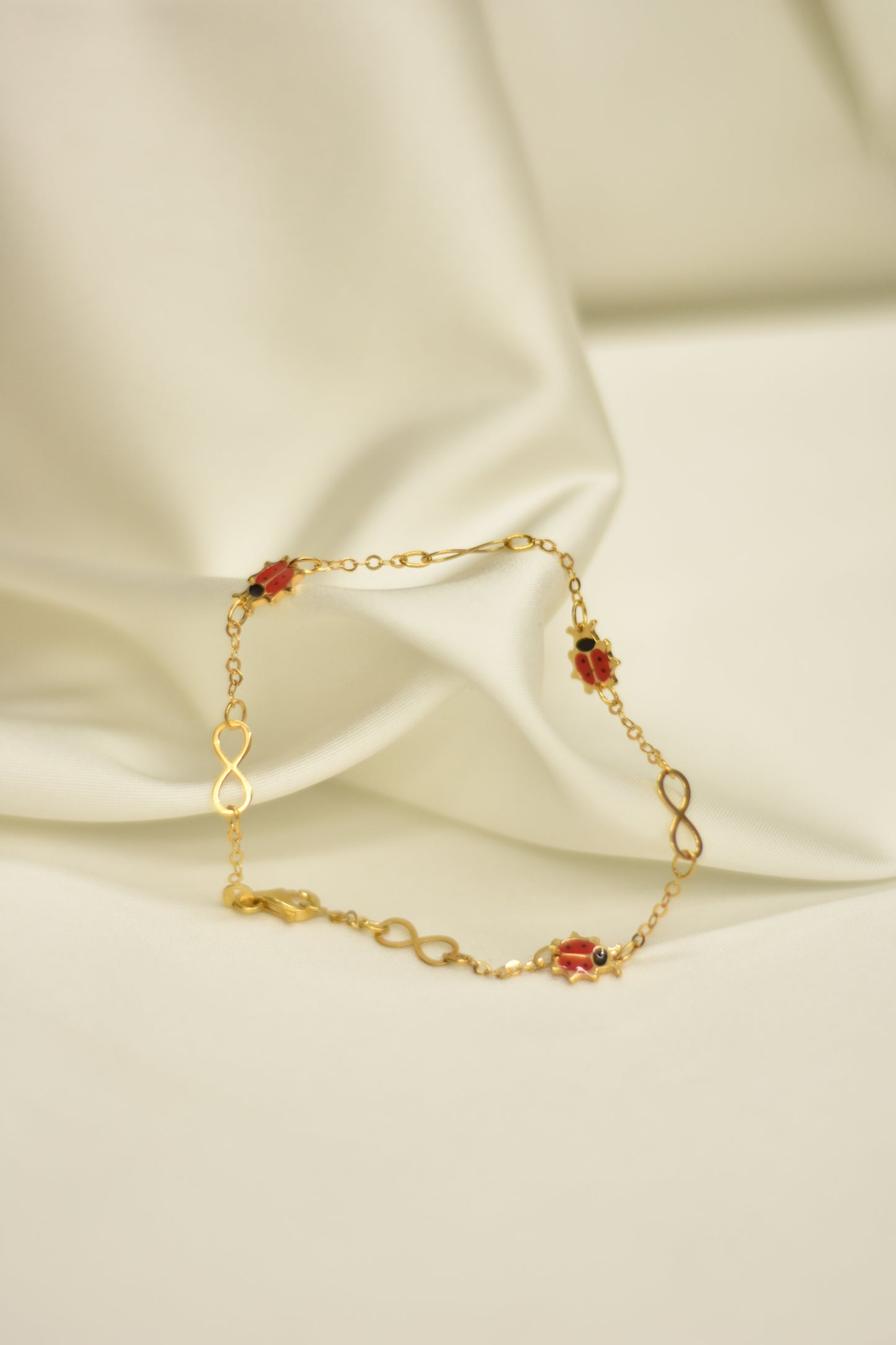 Pulsera con catarinas e infinitos de oro 10k